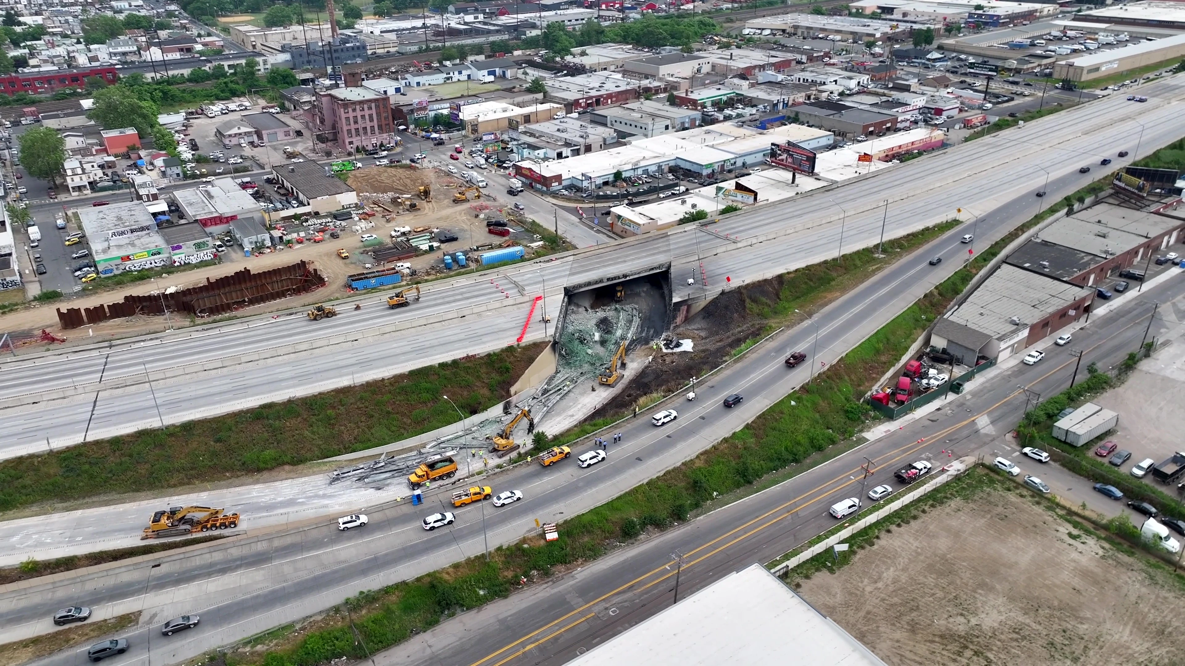 An aerial image of the collapsed section of I-95 with large pieces of construction equipment working to remove debris from the site