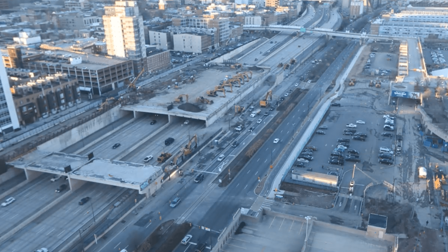 An aerial image showing various pieces of construction equipment staged atop an existing covered area over Interstate 95 in Philadelphia, while construction crews work to demolish areas along the interstate