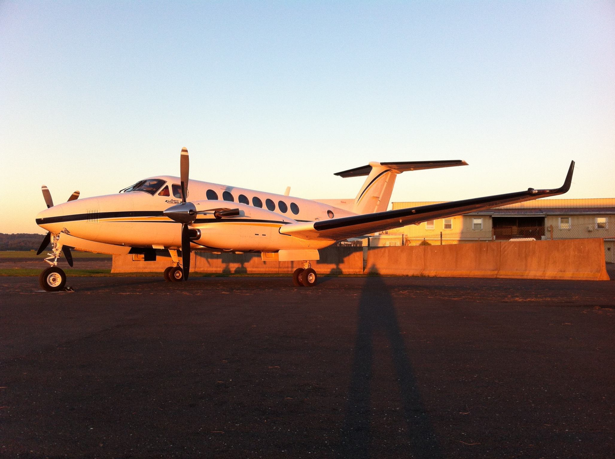 An image of a small plane sitting on an airport's tarmac at sunset
