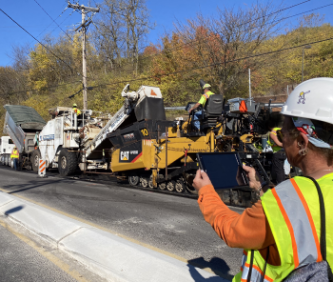 Crew member taking an iPad picture of paving operations